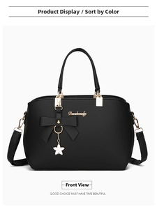 Detail of black lychee grain leather handbag with bow decoration and star charm