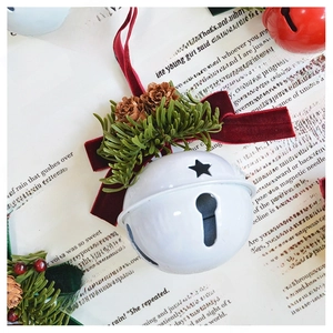 Detail of Christmas bell ornament with red velvet bow, pine needles and pine cones