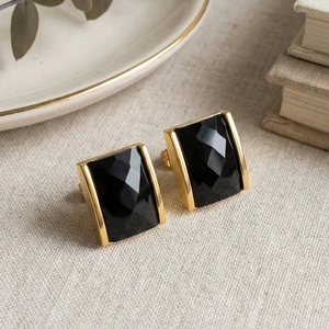 Detailed close-up of rectangle black faceted gemstone earrings with matte 18K gold plated trim