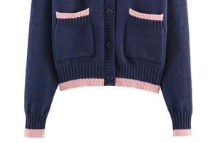 Détail d'un cardigan en maille avec bordures roses contrastées et poches bleu marine