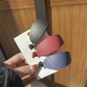 Three matte banana hair clips in black, red, and blue colors on a display card
