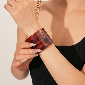Macro detail of wide leopard print acetate cuff bracelet showing red-brown tortoise texture