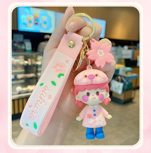 Close-up of cute pink cherry blossom girl keychain with sakura soft strap and gold metal