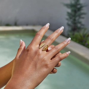 Detail of adjustable 18K gold stainless steel angel wing ring on a hand by the pool