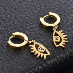 Golden eye-shaped earrings with blue sapphire accents on premium black leather