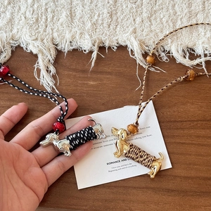 Détail du pendentif teckel tressé avec des finitions métalliques dorées et argentées