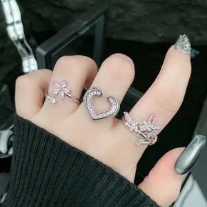 Close-up of three pink zircon rings with butterfly and flower designs on a hand