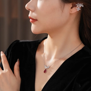 Detail of silver necklace with red teardrop gem and matching floral ear cuff set