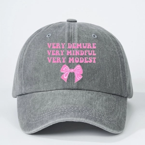 Washed grey baseball cap with pink Very Demure lettering and a small bow design