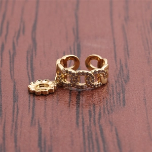 Macro detail of gold chain ring featuring a pavé zircon band and a daisy charm detail