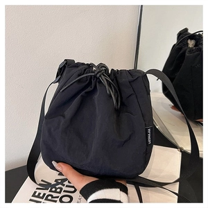 Detail of black nylon drawstring bucket bag with side label and soft texture