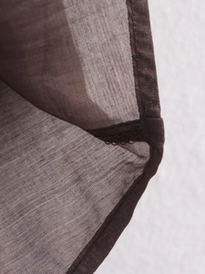 Detailed macro view of dark brown semi-transparent chiffon fabric with fine hemmed stitching