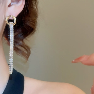 Detail view of long tassel earrings with sparkling crystals on gold metal base