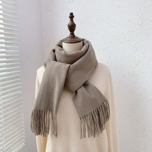 Detail view of camel knit scarf with tassel fringe tied on a mannequin neck