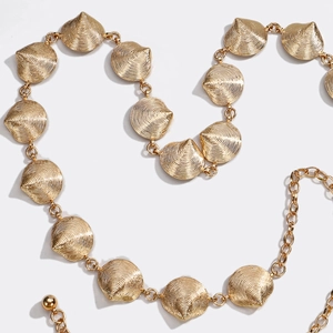 Detail of golden shell-shaped metal chain belt with adjustable links on white background
