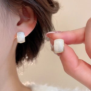 Close-up of elegant ivory resin rectangular earrings with gold-plated metal edges