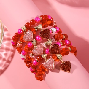 Detail of red and pink beaded layered bracelets with heart charm on a display stand