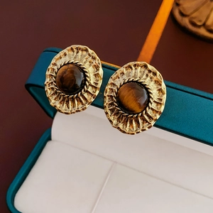 Détail macro de boucles d'oreilles vintage en or avec oeil de tigre sur boîte à bijoux