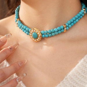 Gros plan sur un collier de perles turquoise à deux rangs avec pendentif en strass doré
