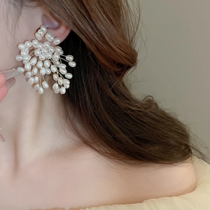 Detailed view of woven floral pearl earrings on model highlighting intricate gold wire design