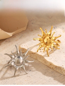 Detailed view of sunburst-shaped 18K gold and silver rings on stone and wood pedestals