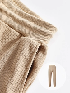 Detailed macro view of waffle texture fabric and elastic waistband on khaki joggers
