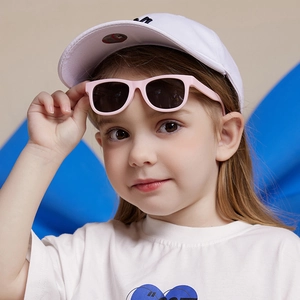 Toddler silicone sunglasses with pink frames and grey lenses worn by kid in white tee