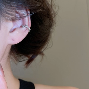 Close-up of silver ear bone clip with marquise zircon and pearls on a female ear
