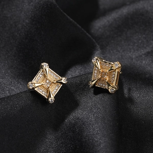 Close-up of golden dragon claw earrings with square zircons on black satin background