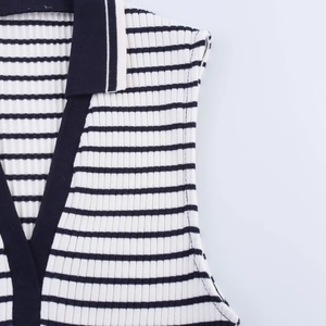 Detail of black and white ribbed knit polo collar with precise stitching and fabric texture