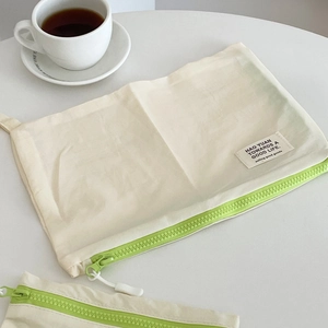 Detalle de bolsas de nailon blanco crema con cremalleras verdes fluorescentes