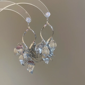 Detailed silver leaf tassel earrings with cubic zirconia on a transparent display stand