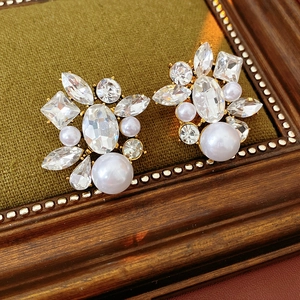 Close-up of vintage baroque pearl earrings with sparkling crystals on dark velvet