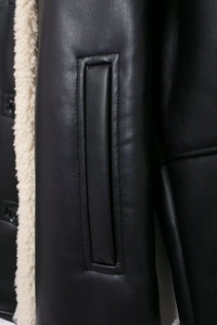 Detail of the white shearling lining and premium leather stitching on a black jacket