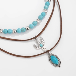 Macro shot of bohemian necklace set featuring silver cactus and turquoise stone charms