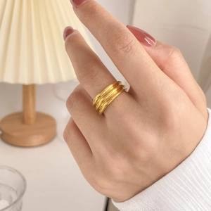 Close-up of golden multi-layer wave ring worn on finger with soft warm lighting