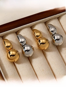 Macro shot of polished gold and silver gourd earrings on a beige velvet jewelry display
