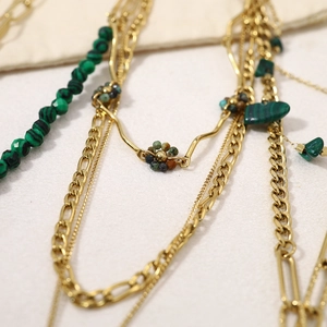 Détail de perles de malachite et chaînes dorées dans un ensemble de colliers