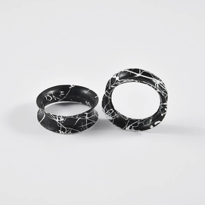 Macro detail of silicone ear tunnels featuring unique black and white ink splatter patterns