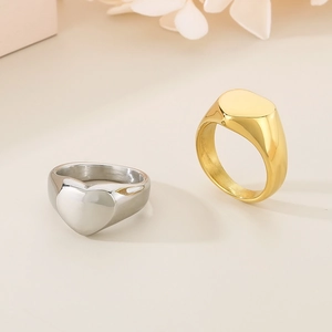 Bagues minimalistes en or et argent sur fond beige chaud avec fleurs décoratives