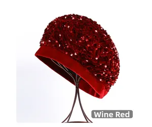 Detail view of wine red sequin beret with sparkling texture on a metal display stand