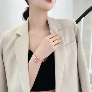 Close-up of pink strawberry quartz bracelet with pearl charms on woman's wrist