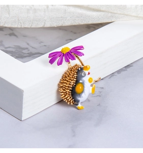 Macro shot of an enamel hedgehog brooch holding a colorful floral umbrella ornament