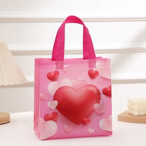 Pink non-woven Valentine's gift bag with red and white heart patterns and sturdy handles