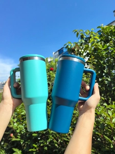 Outdoor shot of two large insulated stainless steel tumblers in teal and navy blue