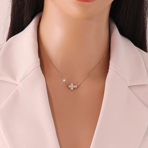 Nahaufnahme einer goldenen Kreuzkette mit Zirkonia-Steinen am Hals eines Models