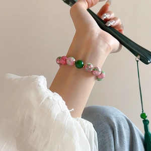 Detailed view of red and green gradient glass bead bracelet with gold-plated accents