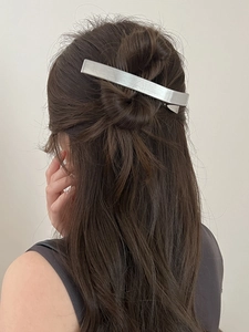 Gros plan d'une pince à cheveux rectangulaire en métal brossé argenté sur une coiffure