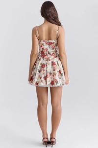 Back view of a white floral mini dress with red and yellow prints and thin straps