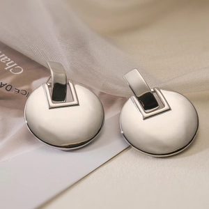 Silver geometric metal drop earrings with polished finish on a minimalist magazine background